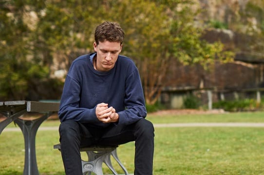young person sitting on bench looking down